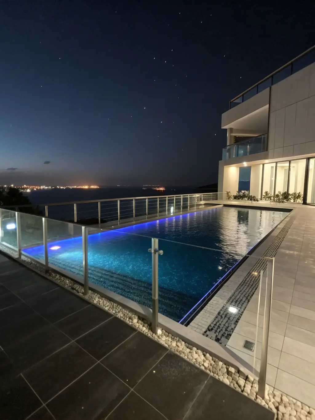 An infinity pool at a luxury hotel in Pattaya, overlooking the city skyline at night. The scene should convey exclusivity and high-end accommodation.